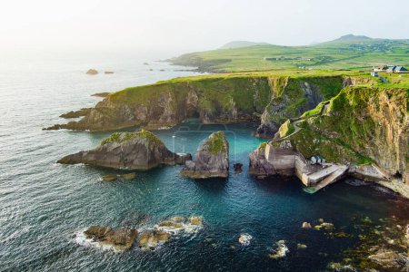 Photo for Dunquin or Dun Chaoin pier, Ireland's Sheep Highway. Aerial view of narrow pathway winding down to the pier, ocean coastline, cliffs. Popular iconic location on Slea Head Drive and Wild Atlantic Way. - Royalty Free Image