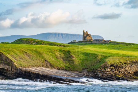 Famoso castillo de Classiebawn en pintoresco paisaje de Mullaghmore Head. Espectacular vista al atardecer con enormes olas rodando en tierra. Punto de firma de Wild Atlantic Way, Co. Sligo, Irlanda