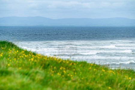 Téléchargez les photos : D'énormes vagues se déferlent sur Tullan Strand, l'une des célèbres plages de surf de Donegal, encadrée par une toile de fond pittoresque fournie par les montagnes Sligo-Leitrim. Large plage de sable plat dans le comté de Donegal, Irlande. - en image libre de droit