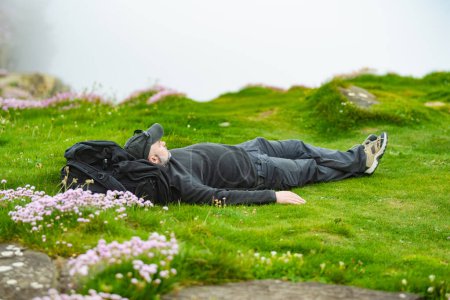 Photo for Tourist enjoying his time on the famous Cliffs of Moher, one of the most popular tourist destinations in Ireland. Foggy view of widely known attraction on Wild Atlantic Way in County Clare. - Royalty Free Image