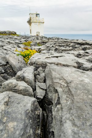 Black Head Lighthouse, situated in the rough rocky landscape of Burren, amidst a bizarre scenery of steep limestone mountains and rocky coastline, County Clare, Ireland.