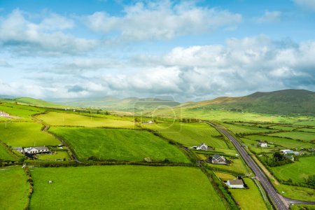 Photo for Aerial view of endless lush pastures and farmlands of Ireland's Dingle Peninsula. Beautiful Irish countryside with emerald green fields and meadows. Rural landscape on sunset. - Royalty Free Image