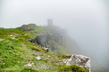 Moher Tower at Hag's Head on the famous Cliffs of Moher, one of the most popular tourist destinations in Ireland. Foggy view of widely known attraction on Wild Atlantic Way in County Clare.