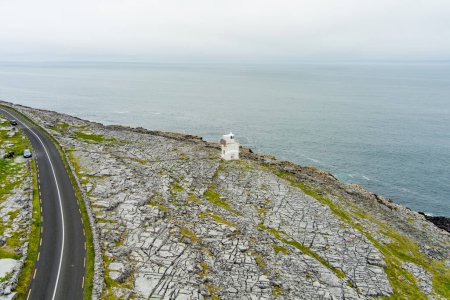 Black Head Lighthouse, gelegen in der rauen Felslandschaft von Burren, inmitten einer bizarren Landschaft aus steilen Kalksteinbergen und felsiger Küste, County Clare, Irland.