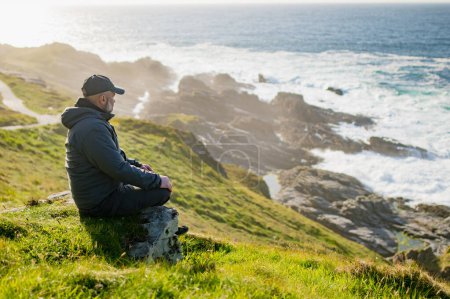 Téléchargez les photos : Touriste admirant la beauté pittoresque de Malin Head, point le plus au nord de l'Irlande, Wild Atlantic Way, route côtière spectaculaire. Merveilles de la nature. De nombreux points de découverte. Co. Donegal - en image libre de droit