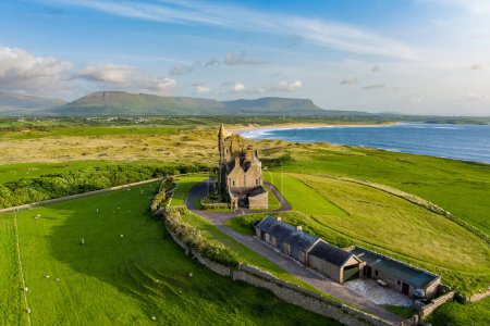 Photo for Classiebawn Castle on a backdrop of picturesque landscape of Mullaghmore Head. Spectacular sunset view with huge waves rolling ashore. Signature point of Wild Atlantic Way, Co. Sligo, Ireland - Royalty Free Image