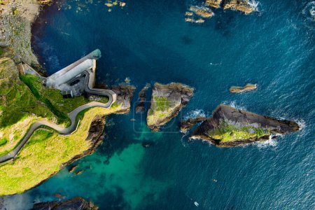 Photo for Dunquin or Dun Chaoin pier, Ireland's Sheep Highway. Aerial view of narrow pathway winding down to the pier, ocean coastline, cliffs. Popular iconic location on Slea Head Drive and Wild Atlantic Way. - Royalty Free Image