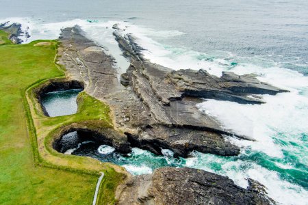 Aerial view of Bridges of Ross, three natural rock arches, carved into the cliffs by natural ocean erosion, on the west coast of Ross Bay, Wild Atlantic Way Discovery Point, County Clare, Ireland