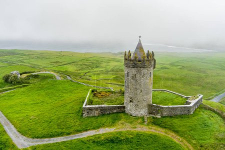 Aerial view of Doonagore Castle, round 16th-century tower house with a small walled enclosure located near the coastal village of Doolin in County Clare, Ireland.