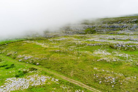 Foto de Espectacular paisaje aéreo brumoso en la región de Burren del Condado de Clare, Irlanda. Expuesto kárstico roca caliza en el Parque Nacional de Burren. Naturaleza irlandesa áspera. - Imagen libre de derechos