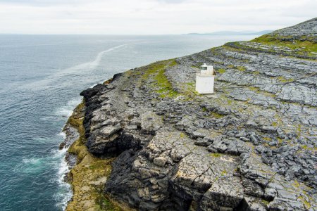 Téléchargez les photos : Phare de Black Head, situé dans le paysage rocheux rugueux de Burren, au milieu d'un paysage étrange de montagnes calcaires abruptes et de côtes rocheuses, comté de Clare, Irlande. - en image libre de droit