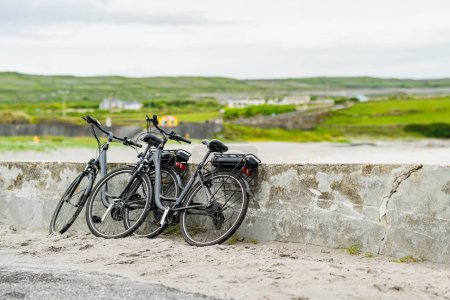 Téléchargez les photos : Deux vélos électriques stationnés sur Inishmore, la plus grande des îles Aran à Galway Bay, en Irlande. Louer un vélo est l'un des moyens les plus populaires pour se déplacer Inis Mor. - en image libre de droit