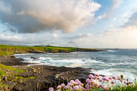Photo for Famous Classiebawn Castle in picturesque landscape of Mullaghmore Head. Spectacular sunset view with huge waves rolling ashore. Signature point of Wild Atlantic Way, Co. Sligo, Ireland - Royalty Free Image