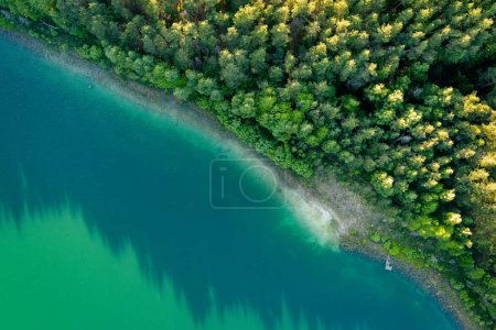 Foto de Vista aérea de hermosas aguas verdes del lago Gela. Vista panorámica de aves del lago esmeralda rodeado de bosques de pinos. Nubes reflejadas en el lago Gela, cerca de la ciudad de Vilna, Lituania. - Imagen libre de derechos