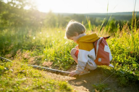 Photo for Cute little boy with a backpack having fun outdoors on sunny summer day. Child exploring nature. Kid going on a trip. Summer activities for families with kids. - Royalty Free Image