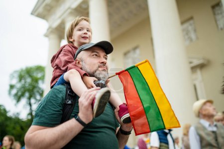 Téléchargez les photos : Cute little boy and his father holding tricolor Lithuanian flag celebrating Lithuanian Statehood Day, Vilnius, Lithuania - en image libre de droit