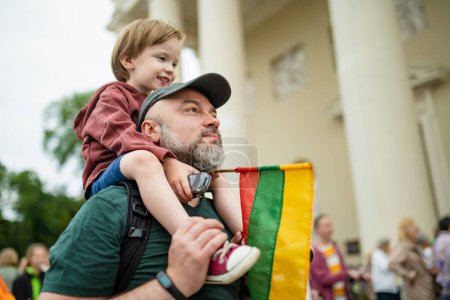 Cute little boy and his father holding tricolor Lithuanian flag celebrating Lithuanian Statehood Day, Vilnius, Lituania