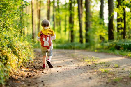 Photo for Cute little boy with a backpack having fun outdoors on sunny summer day. Child exploring nature. Kid going on a trip. Summer activities for families with kids. - Royalty Free Image
