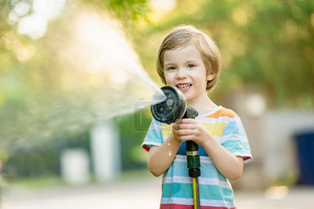 Photo for Cute little boy playing with garden hose on hot summer day. Child playing with water at summertime. Active leisure with little kids. - Royalty Free Image