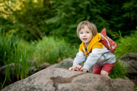 Téléchargez les photos : Petit garçon mignon avec un sac à dos s'amusant à l'extérieur le jour ensoleillé de l'été. Enfant explorant la nature. Le gamin part en voyage. Activités estivales pour les familles avec enfants. - en image libre de droit