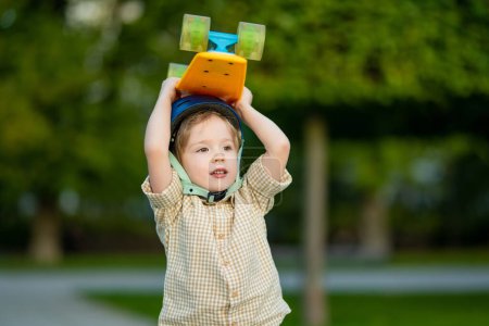 Photo for Cute little boy learning to skateboard on beautiful summer day in a park. Child wearing safety helmet enjoying skateboarding ride outdoors. Active leisure for small kids. - Royalty Free Image