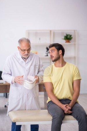Photo for Young neck injured patient visiting old male doctor - Royalty Free Image
