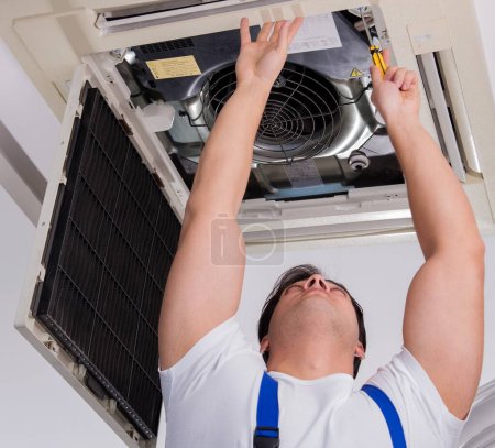 Le travailleur réparer l'unité de climatisation de plafond