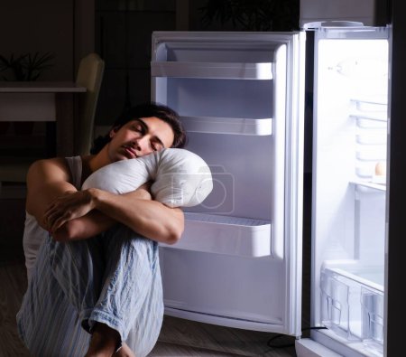 Der Mann bricht nachts in der Nähe des Kühlschranks eine Diät