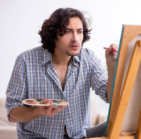 Photo for The young handsome man enjoying painting at home - Royalty Free Image