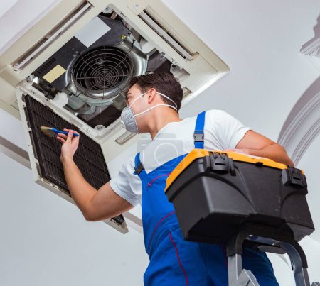 Téléchargez les photos : Le travailleur réparer l'unité de climatisation de plafond - en image libre de droit