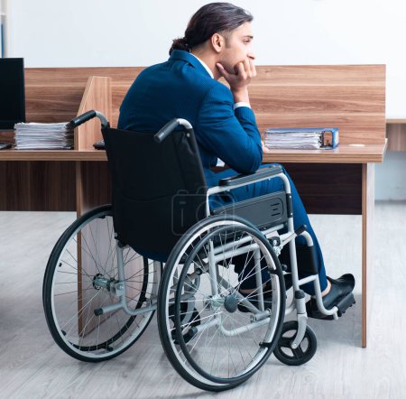 Téléchargez les photos : Le jeune employé masculin en fauteuil roulant - en image libre de droit