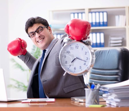 Téléchargez les photos : L'homme d'affaires en colère avec des gants de boxe dans le concept de gestion du temps - en image libre de droit