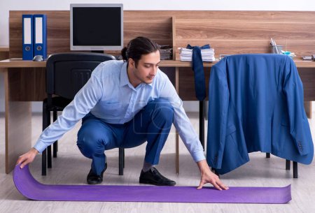 Photo for The young handsome businessman doing exercises at workplace - Royalty Free Image
