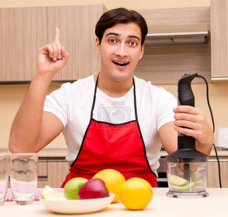 Téléchargez les photos : Le bel homme qui travaille à la cuisine - en image libre de droit