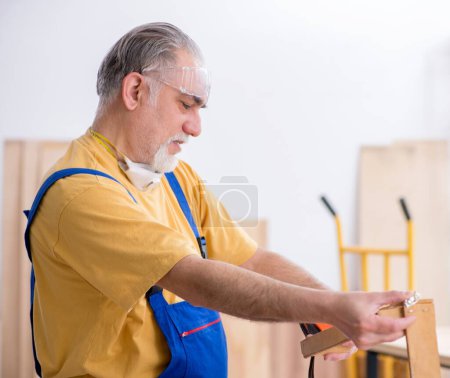 Foto de El viejo carpintero trabajando en el taller - Imagen libre de derechos