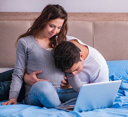 Téléchargez les photos : La jeune famille avec femme enceinte attend bébé au lit - en image libre de droit
