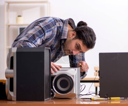 Téléchargez les photos : Le jeune ingénieur répare le système hi-fi musical - en image libre de droit