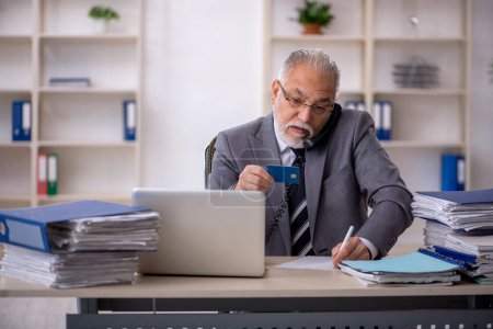 Téléchargez les photos : Un vieil homme d'affaires détenant une carte de crédit au bureau - en image libre de droit