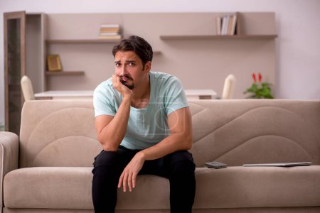 Photo for Young man sitting on the sofa at home - Royalty Free Image