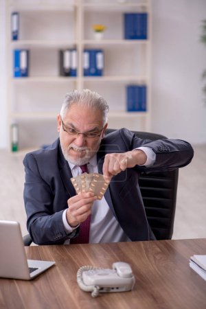 Foto de Viejo empleado sintiéndose mal en el lugar de trabajo - Imagen libre de derechos