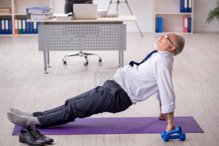 Téléchargez les photos : Ancien employé masculin faisant des exercices sportifs pendant la pause - en image libre de droit
