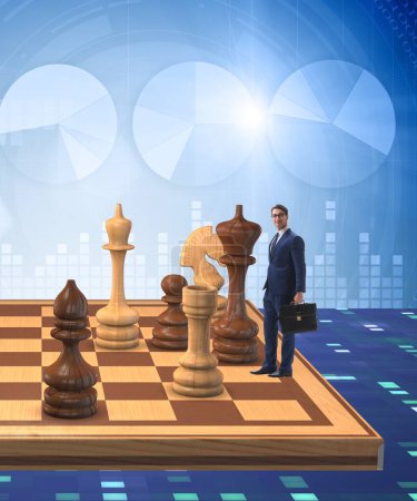 Foto de El hombre de negocios en gran tablero de ajedrez en concepto de estrategia - Imagen libre de derechos