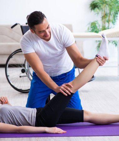Téléchargez les photos : Le physiothérapeute masculin faisant des exercices avec la femme blessée sur le sol - en image libre de droit