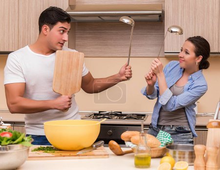 Foto de La joven familia haciendo lucha divertida en la cocina - Imagen libre de derechos
