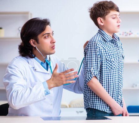 Foto de El médico masculino examinando al niño por estetoscopio - Imagen libre de derechos