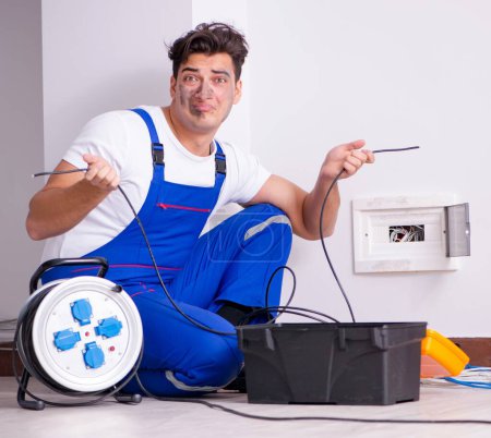 Foto de El hombre gracioso haciendo reparaciones eléctricas en casa - Imagen libre de derechos