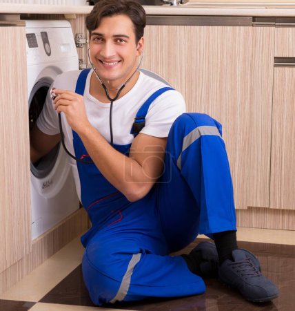 Téléchargez les photos : Le réparateur réparer la machine à laver à la cuisine - en image libre de droit