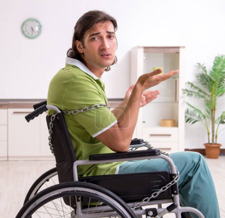 Photo for The young male invalid in wheel-chair suffering at home - Royalty Free Image