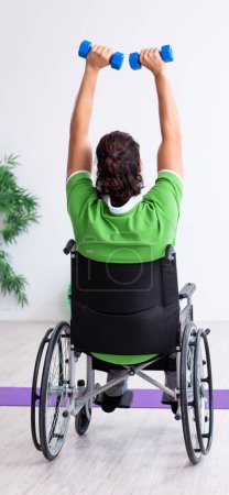 Foto de El joven en silla de ruedas haciendo ejercicios en el interior - Imagen libre de derechos