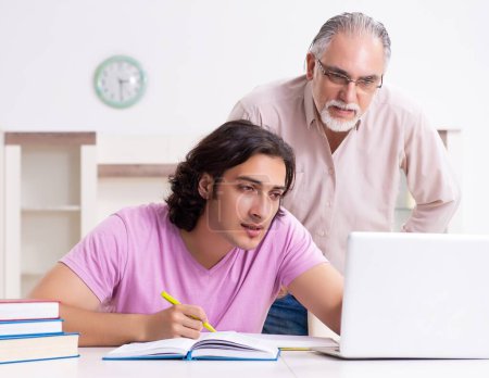Photo for The old father helping his son in exam preparation - Royalty Free Image